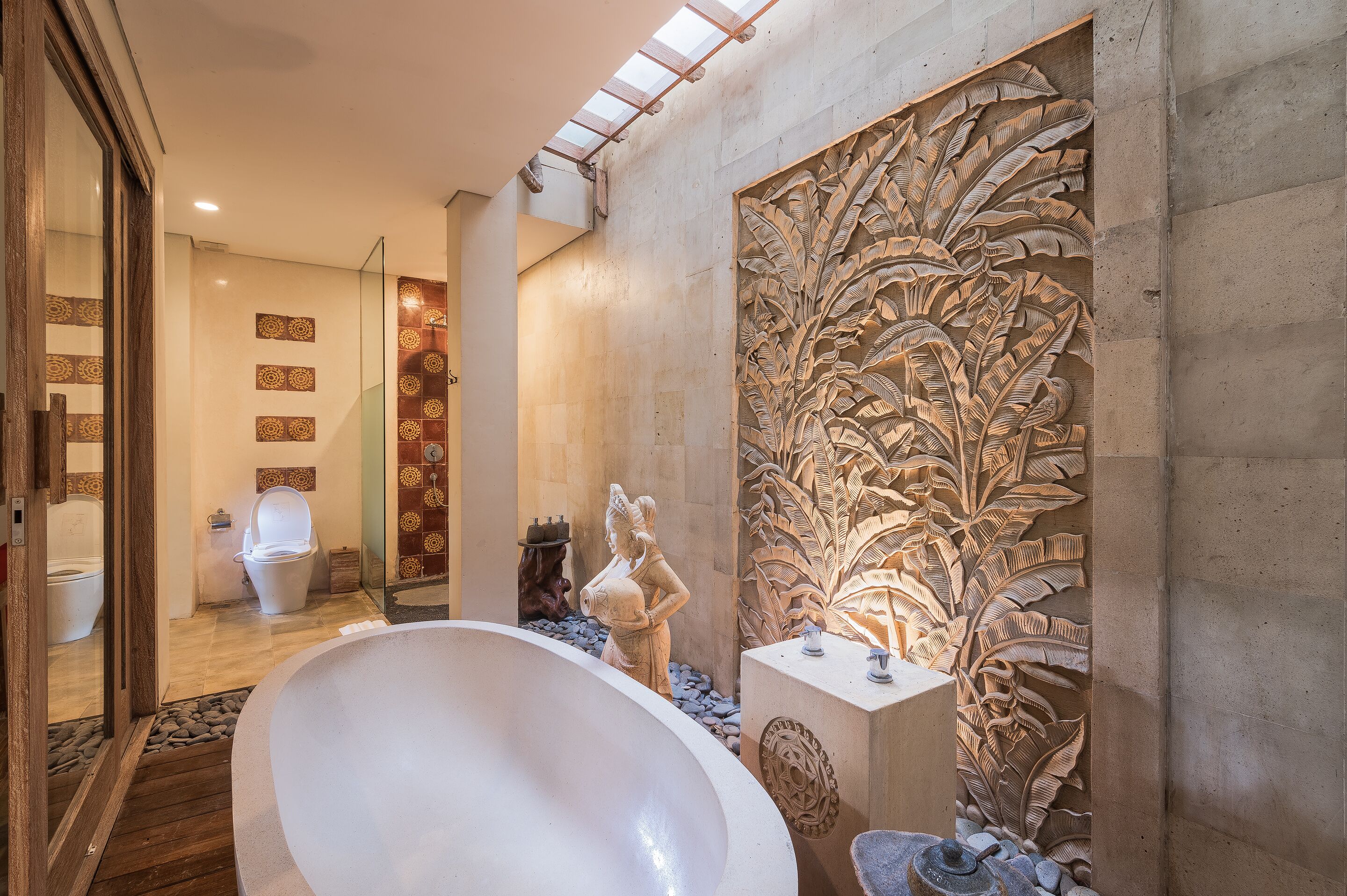 A bathroom with a freestanding bathtub, a decorative wall carving, and a tiled floor.