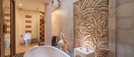 A bathroom with a freestanding bathtub, a decorative wall carving, and a tiled floor.