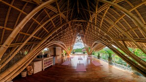 A bamboo structure with a wooden floor and yoga mats. - The Udaya Resorts and Spa (Ubud)