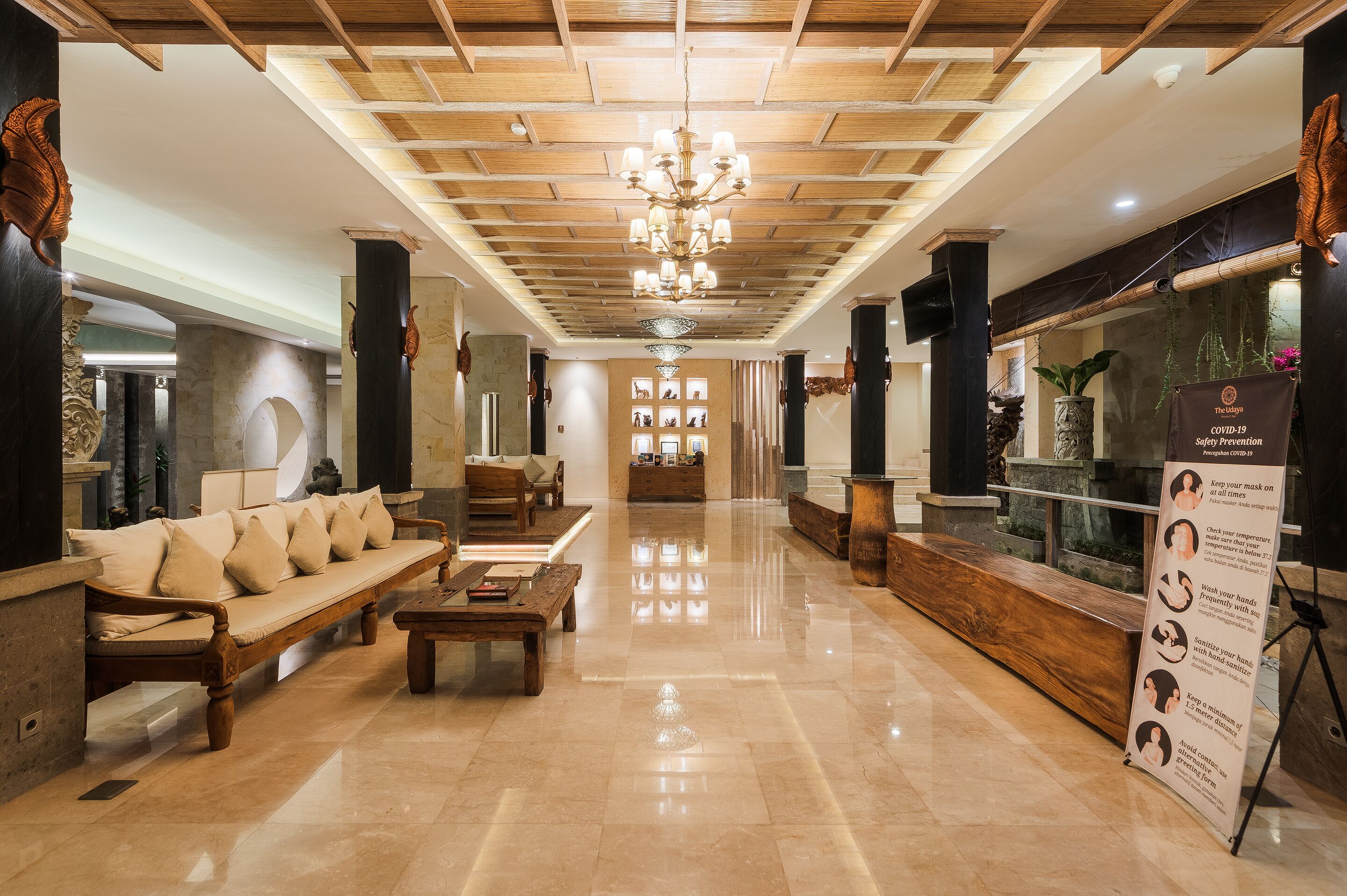 A spacious lobby with a wooden bench, a sofa, and a reception desk.