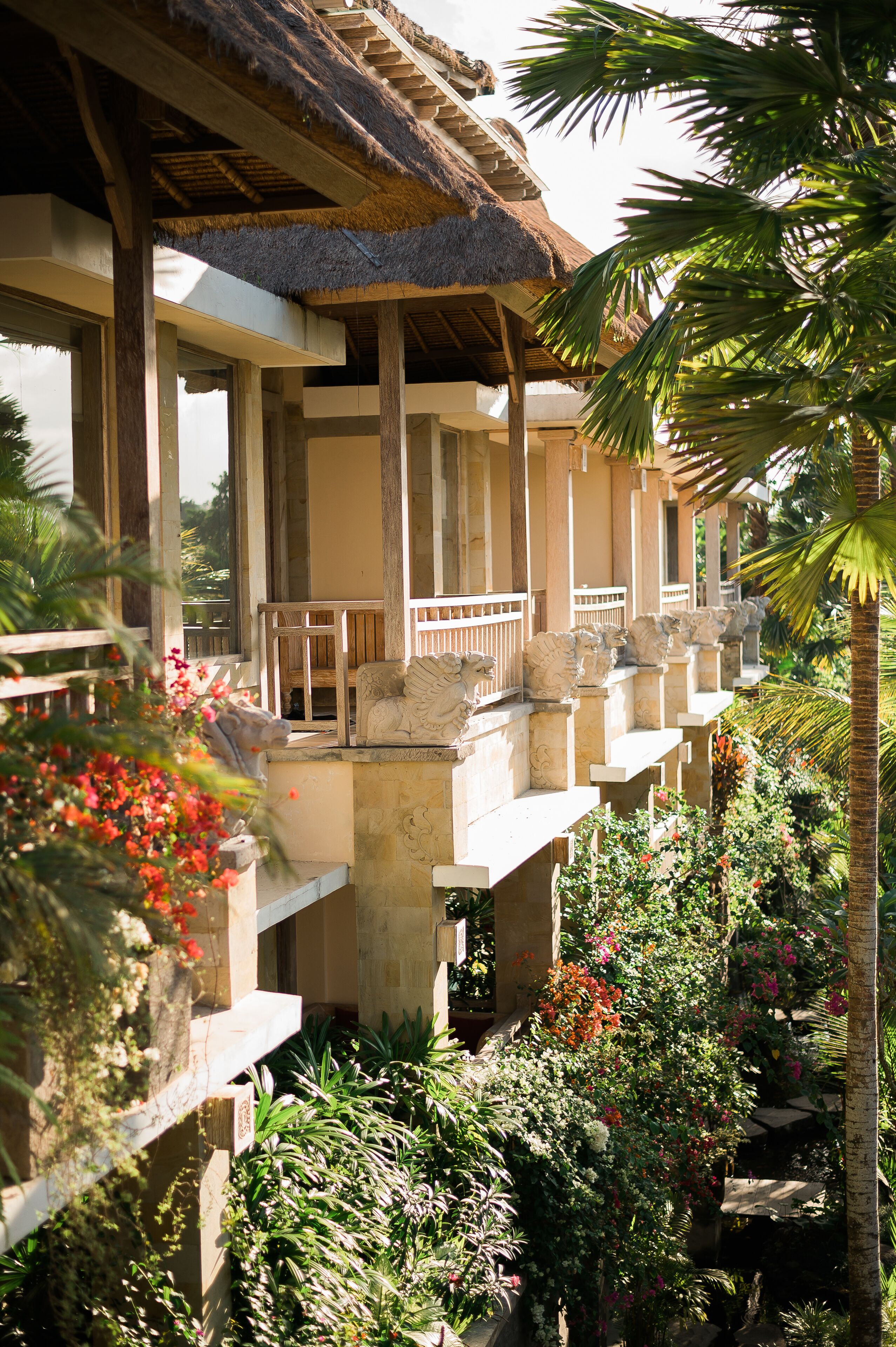 A resort with multiple balconies, lush tropical gardens, and a thatched roof structure.