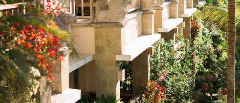 A resort with multiple balconies, lush tropical gardens, and a thatched roof structure.