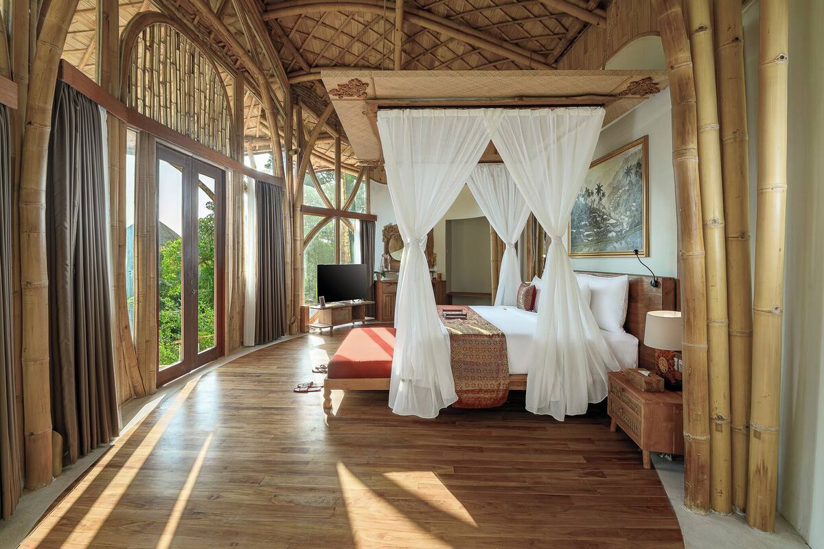 Una habitación amplia con una cama grande, televisión y ventana con cortinas de bambú.