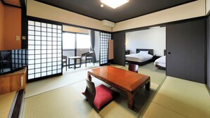 A traditional Japanese room with tatami flooring, a low table, a TV, and a sliding door leading to a bedroom. - Yutorelo Yamaga (Yamaga)