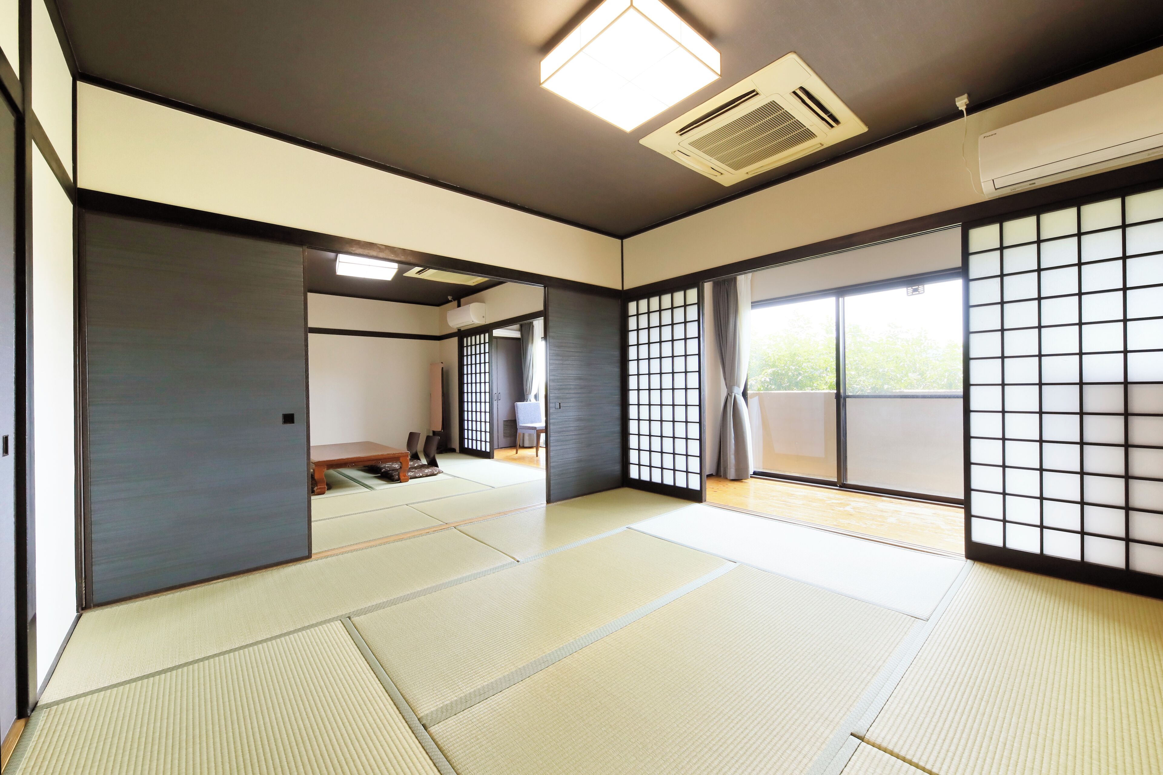 A traditional Japanese room with tatami flooring, sliding doors, and a view of the outdoors.