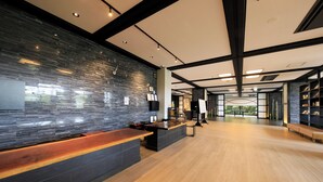 A modern reception area with a stone wall, wooden reception desk, and a spacious interior with a high ceiling and natural light. - Yutorelo Yamaga (Yamaga)