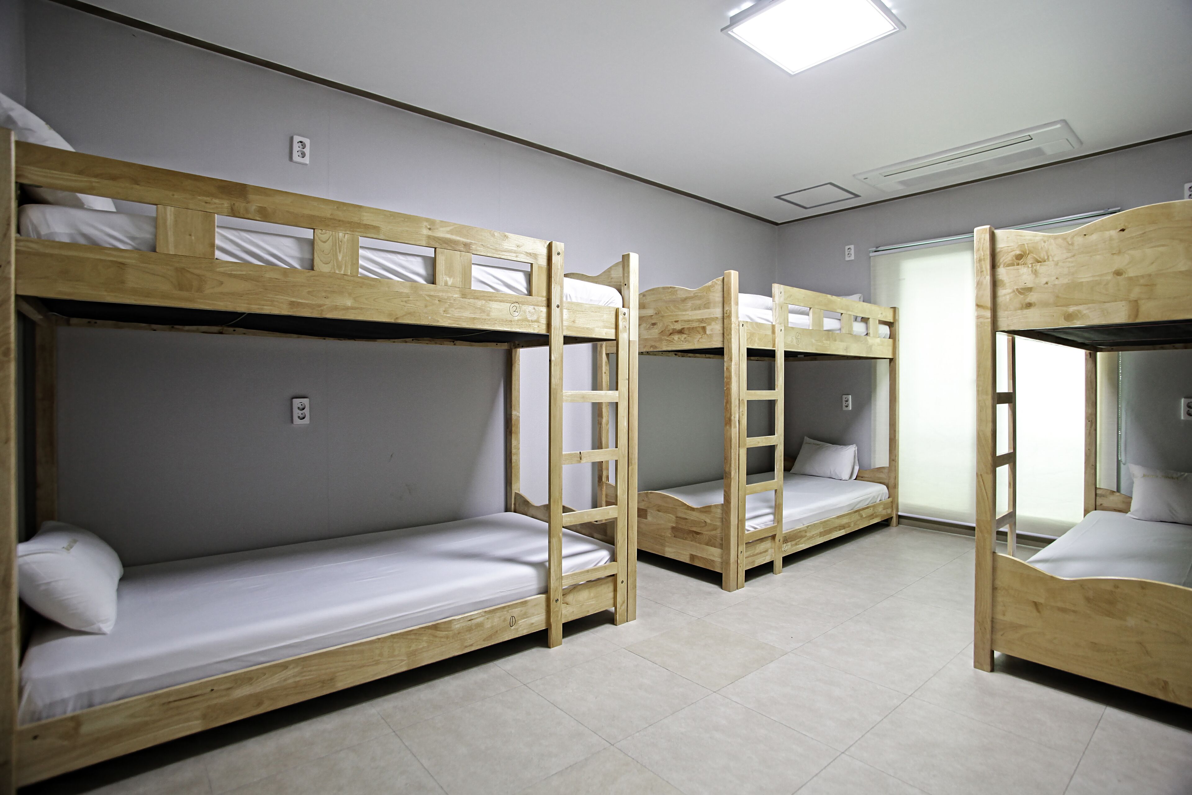 Ein Schlafsaalzimmer mit Etagenbetten, einem Fenster und einer Tür.