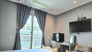 A hotel room with two beds, a desk with a computer, a TV, and an air conditioning unit. - Jeonju Hostel (Jeonju)