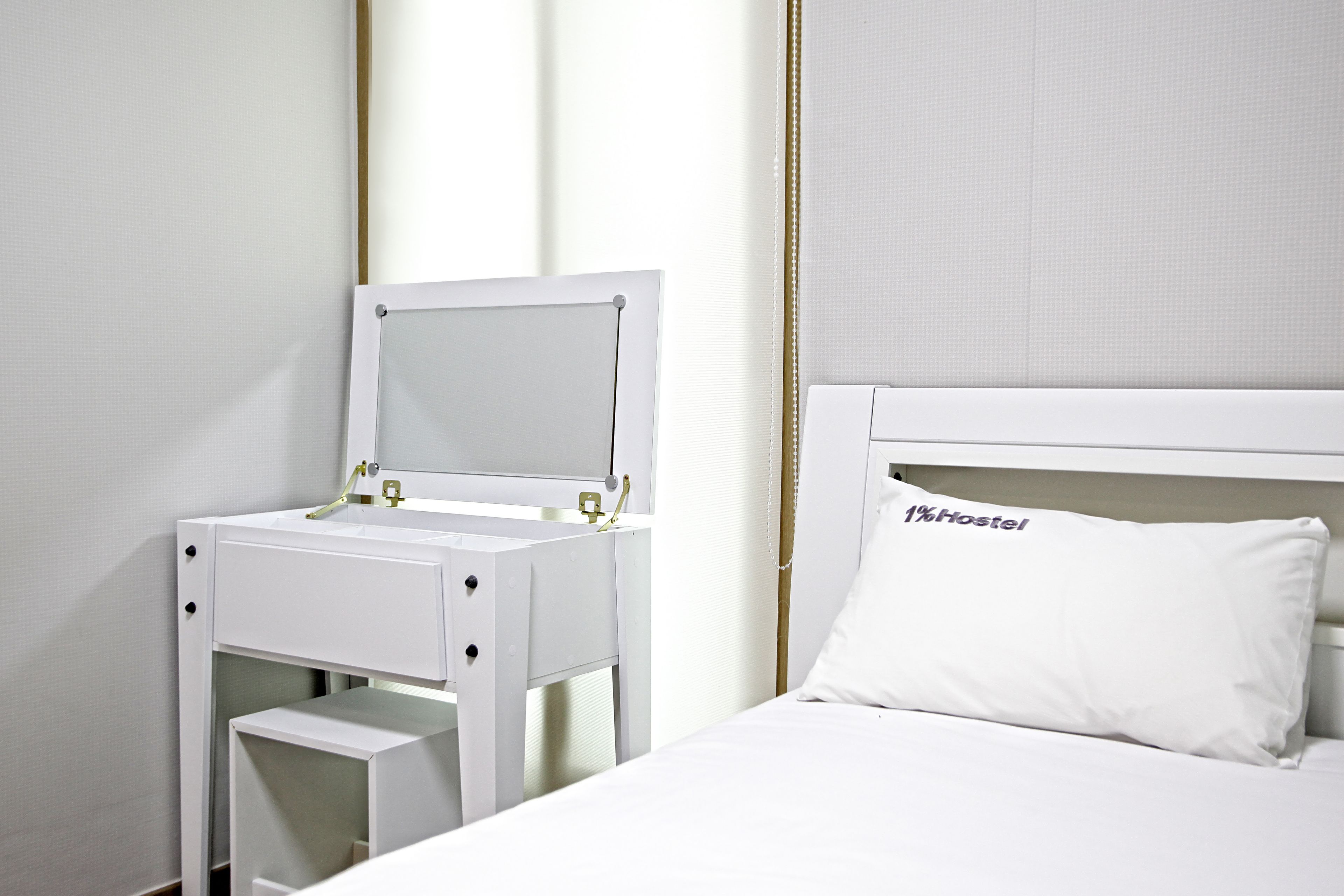 A white bedside table with a mirror, a small drawer, and a nightstand.