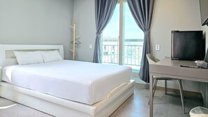 A hotel room with a bed, a desk, a TV, and a window with curtains. - Jeonju Hostel (Jeonju)