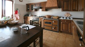 A kitchen with wooden cabinets, a stove, and a dining table with chairs. - B&B Cinqueterre Il filo di Arianna (Ricco del Golfo di Spezia)