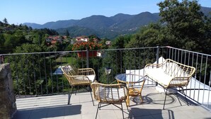 A balcony with wicker furniture and a view of a mountainous landscape. - B&B Cinqueterre Il filo di Arianna (Ricco del Golfo di Spezia)