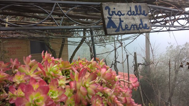 A sign with text in a foreign language, a metal structure overhead, and some greenery in the foreground. - B&B Cinqueterre Il filo di Arianna (Ricco del Golfo di Spezia)
