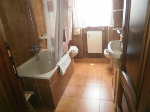 A bathroom with a bathtub, toilet, sink, and a window with curtains. - B&B Cinqueterre Il filo di Arianna (Ricco del Golfo di Spezia)
