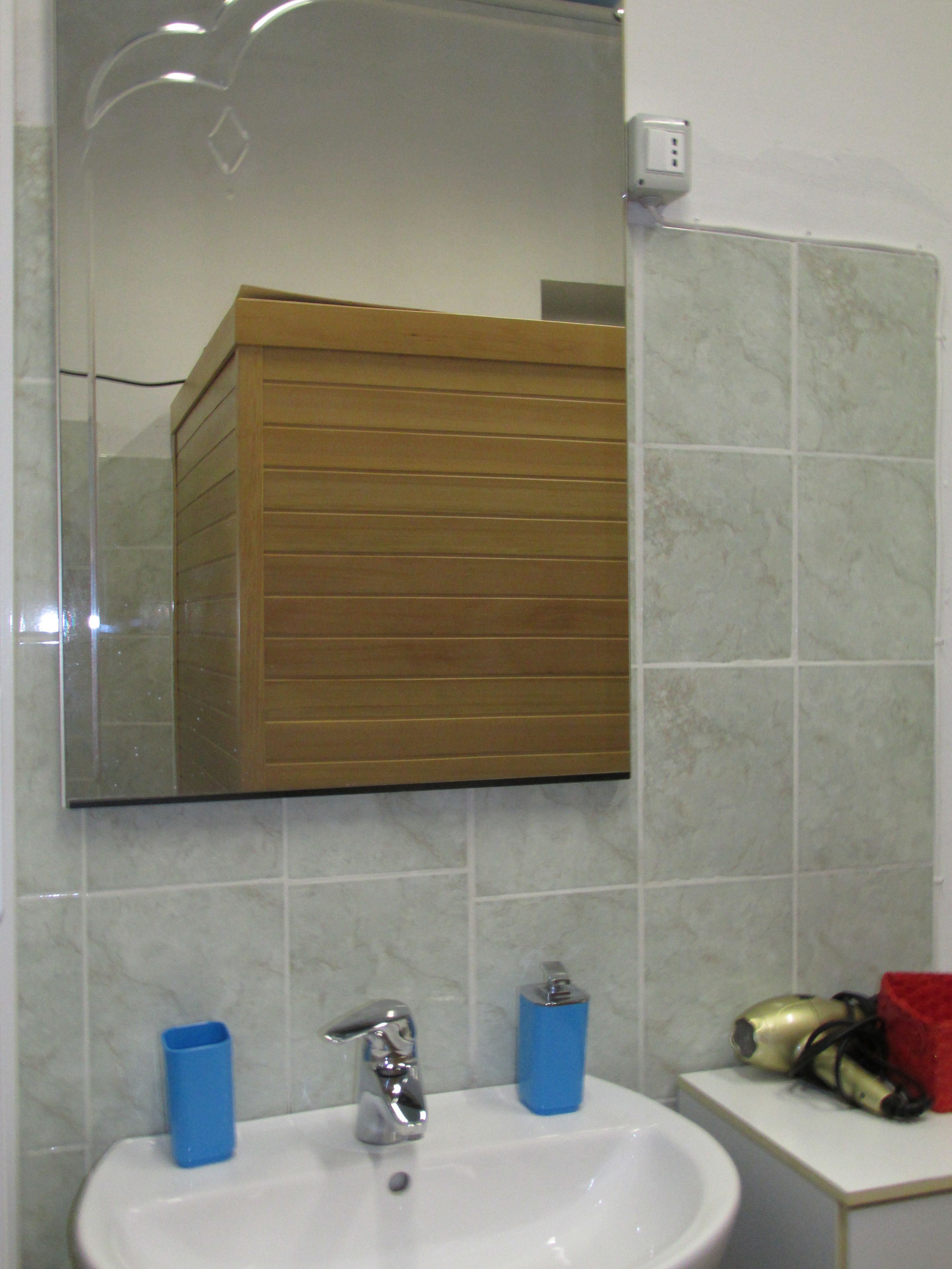 A bathroom with a white sink, a mirror, and a wooden cabinet.