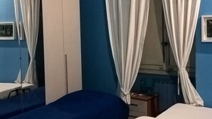 Makuuhuone, jossa on kaksi sänkyä, vaatekaappi ja verhot.