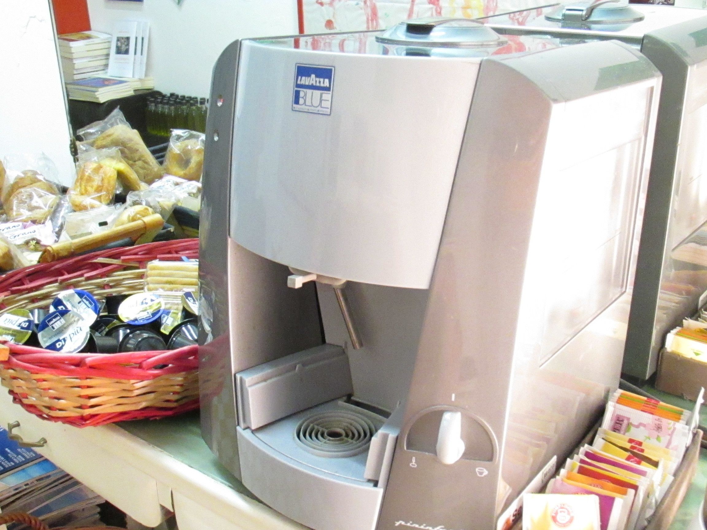 Eine Kaffeemaschine mit blauem Schild, eine Auswahl an Gebäck und ein Bücherstapel.