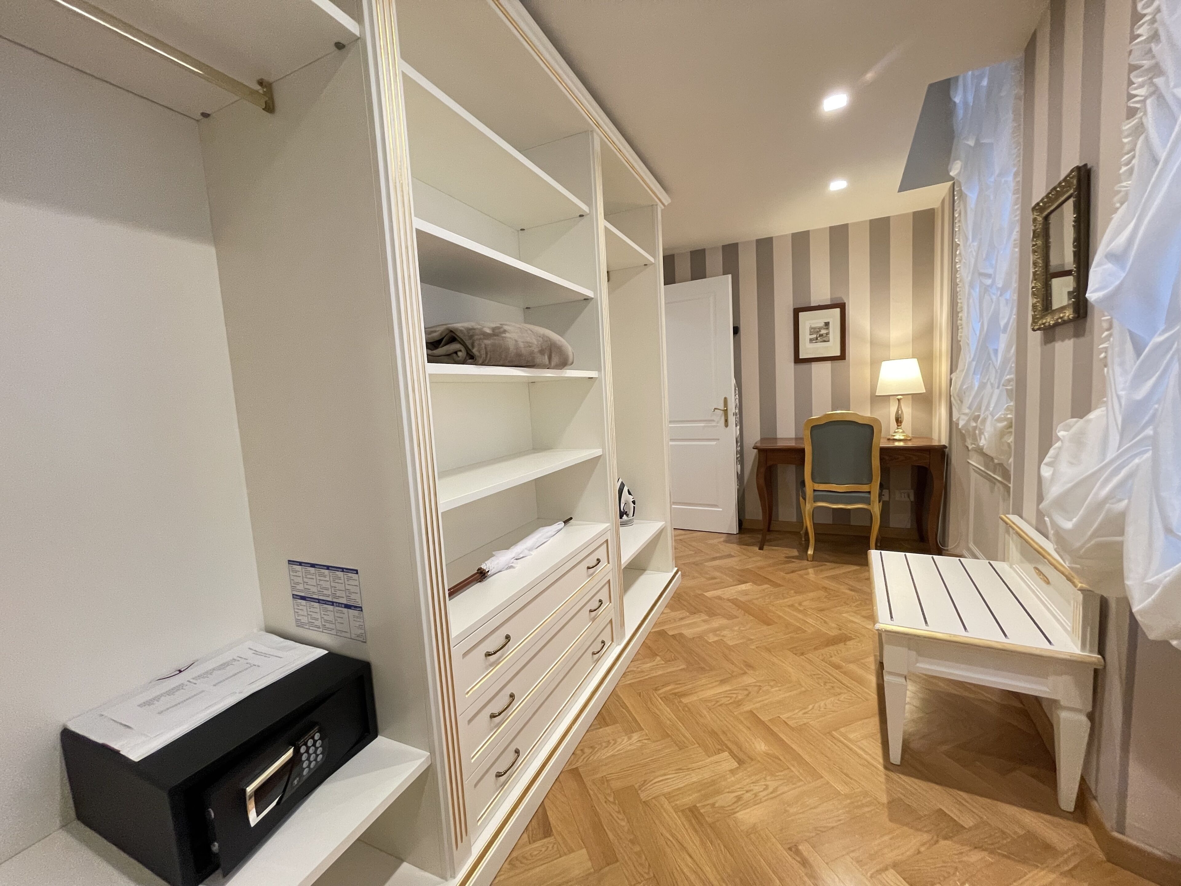 A room with a wardrobe, a desk, a chair, and a bed.