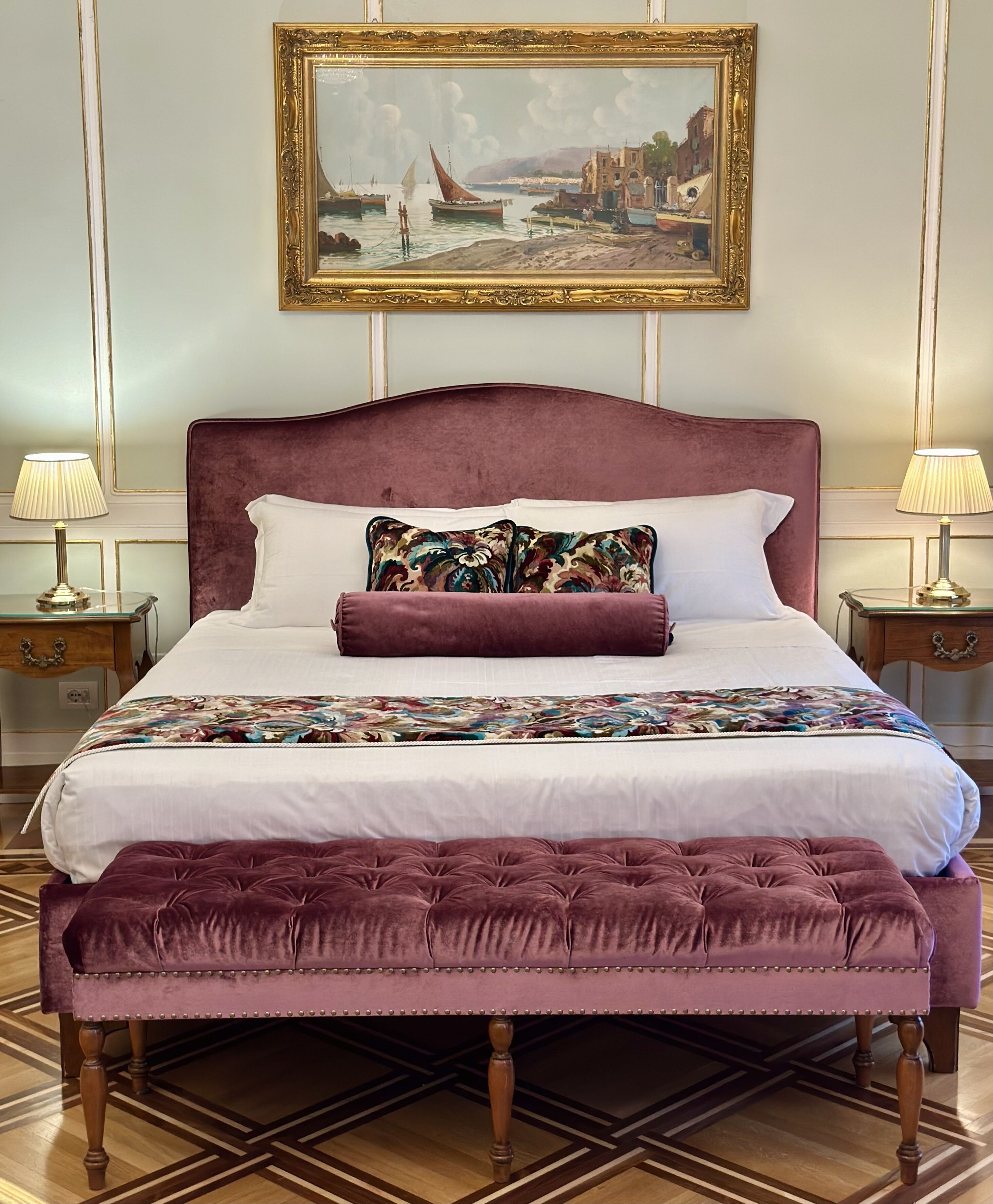 A bed with a large, plush headboard, a matching footboard, and a decorative pillow.