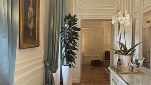 Um corredor com um banco, uma planta em vaso e um quadro na parede.
