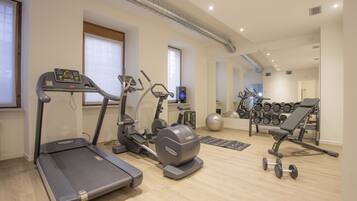 Un gimnasio en casa con cintas de correr, elípticas, una prensa de banca y un estante con mancuernas.