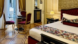 Quarto de hotel com uma cama grande, uma escrivaninha com cadeira, uma mesinha e um guarda-roupa.