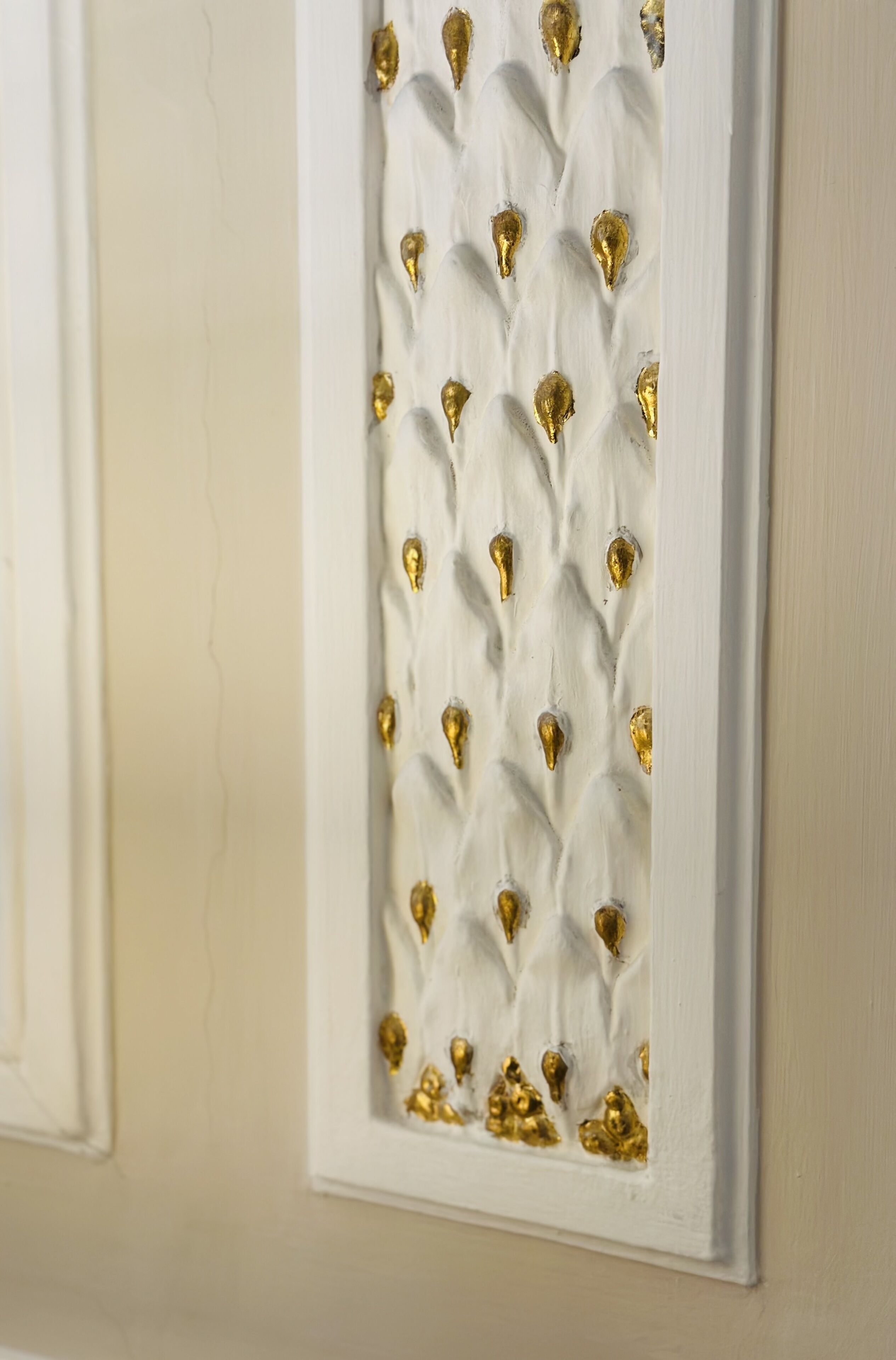 A wall with a decorative panel featuring a textured pattern and gold accents.