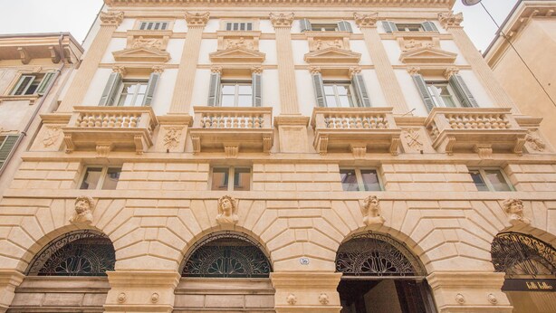 Um edifício clássico com detalhes arquitetônicos elaborados, incluindo colunas, molduras decorativas e janelas em arco.