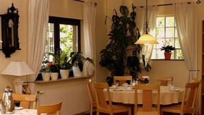 A dining room with a table set for four, surrounded by chairs, a radiator, and potted plants. - Hotel zum Schnackel (Wiesbaden)