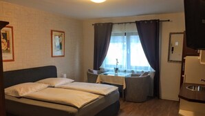 A hotel room with a bed, a small table, a sofa, and a window with curtains. - Hotel zum Schnackel (Wiesbaden)