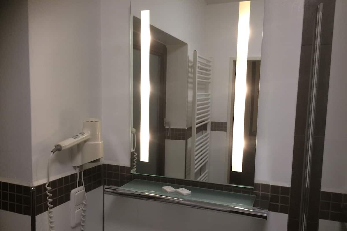 A bathroom with a glass shelf, a hairdryer, and a mirror.