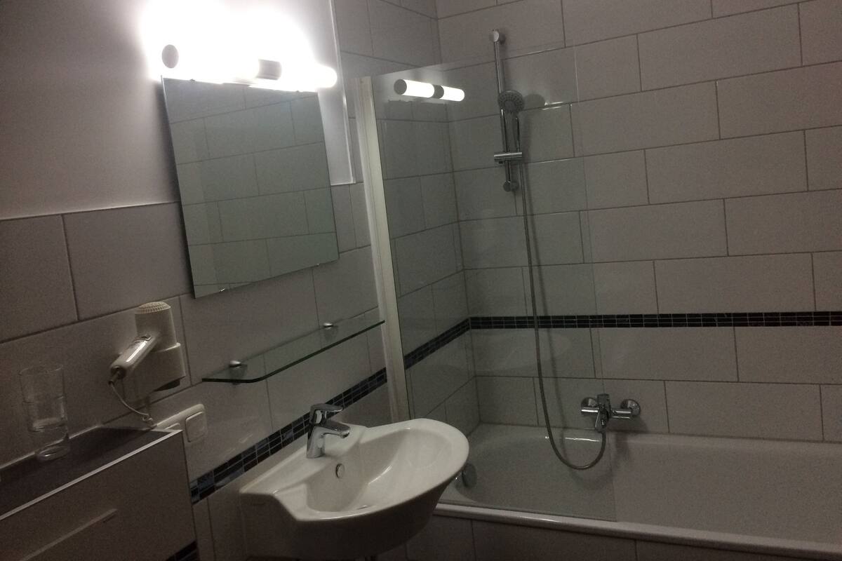 A bathroom with a sink, mirror, and shower.
