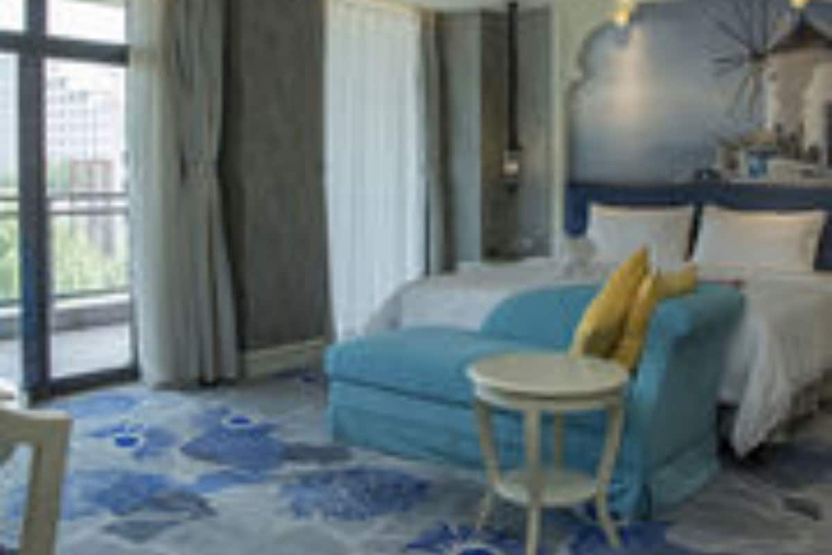 A hotel room with a bed, a small round table, and a view of the outdoors.