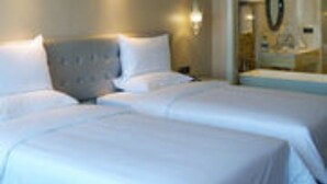 A hotel room with two beds, a large mirror, and a chandelier. - Huaqing Aegean Inter Hot Spring Resort (Xi'an)