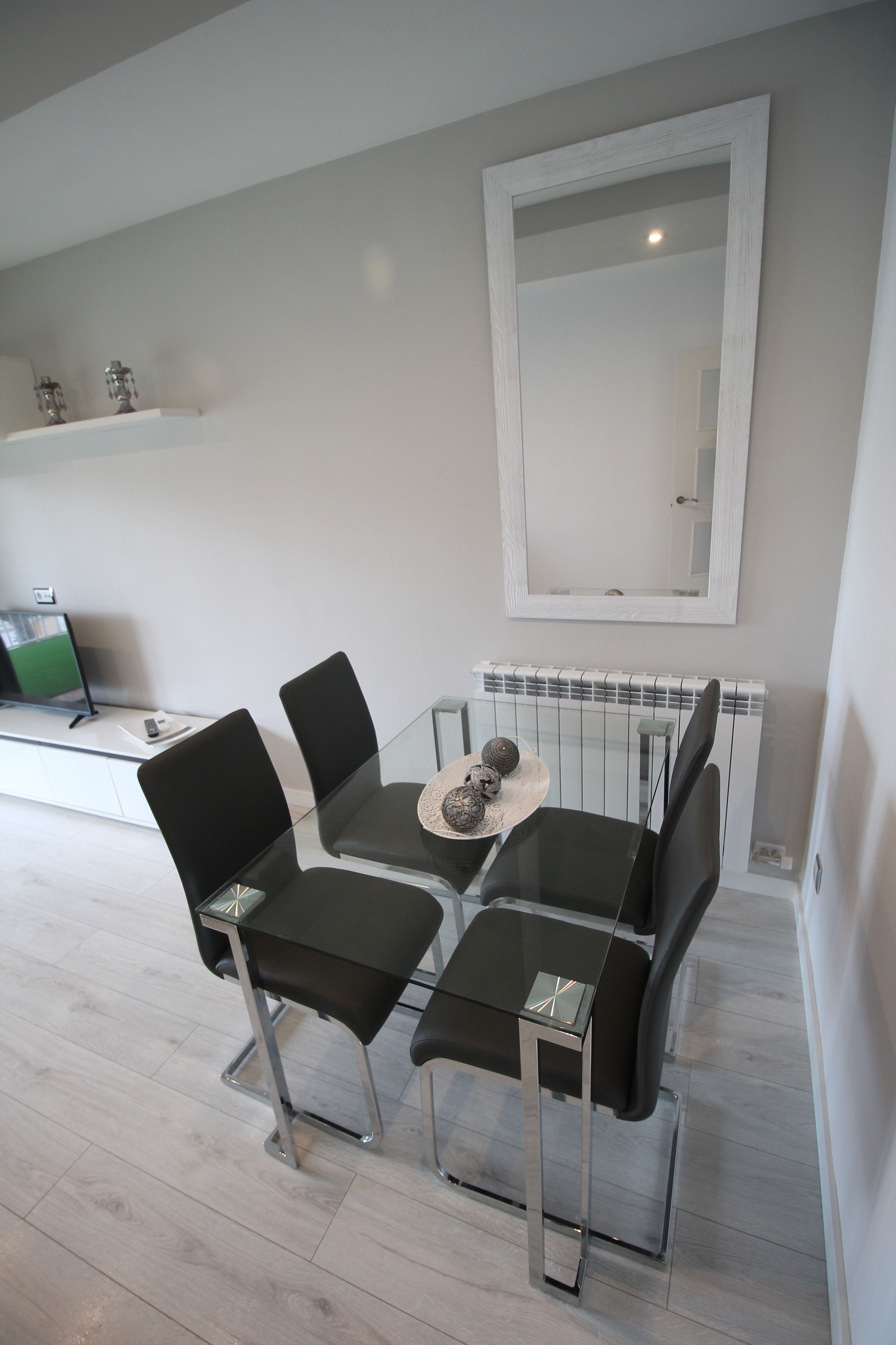 A modern dining area with a glass table, black chairs, and a decorative plate.