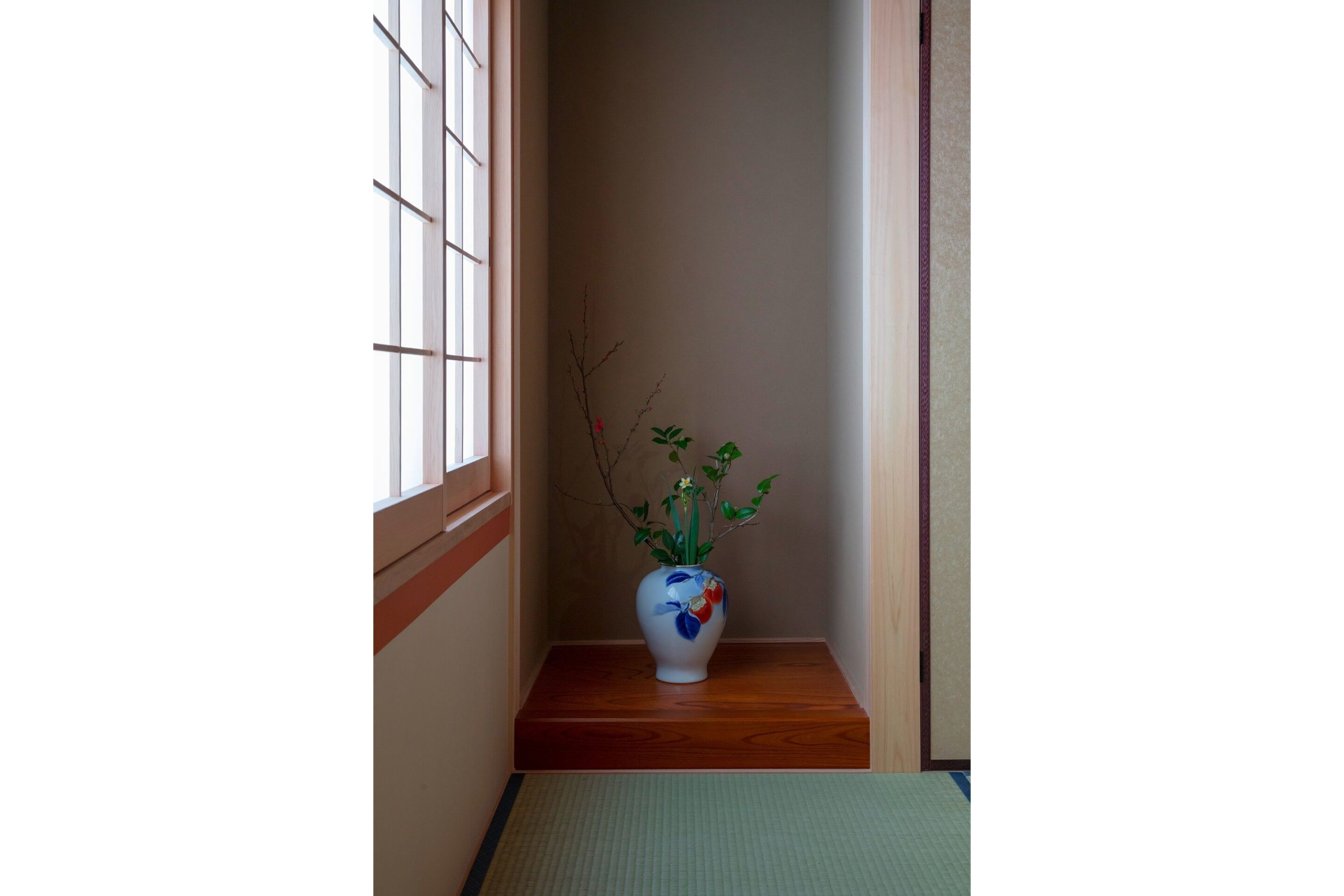 A narrow hallway with a wooden floor, a white vase with a floral design, and a small plant.