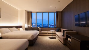 Una habitación de hotel con dos camas, un sofá, una mesita y un televisor.