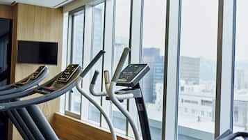 A gym with treadmills and a city view through large windows.