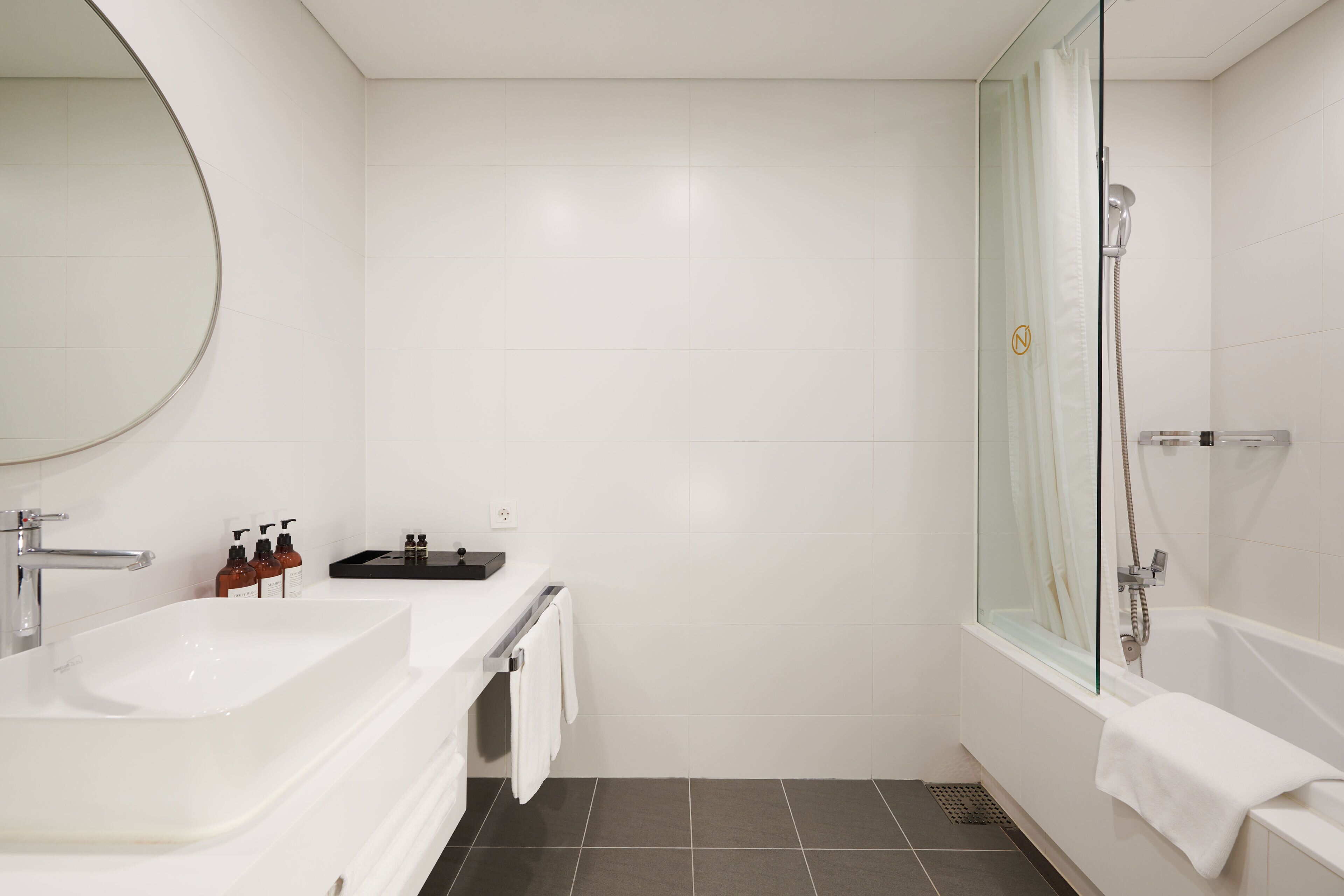 A modern bathroom with a large mirror, two sinks, a shower, and a bathtub.