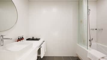 A modern bathroom with a large mirror, two sinks, a shower, and a bathtub.