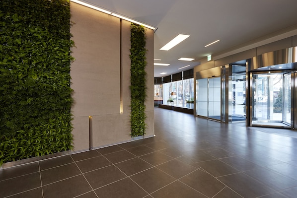 A modern lobby with a green vertical garden, large windows, and a clean tiled floor. - NINE TREE BY PARNAS SEOUL MYEONDONG 2 (Seoul)