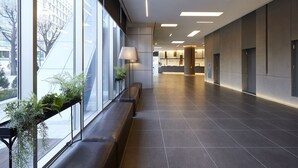 Un interior moderno con un largo banco a lo largo de una pared de vidrio, una lámpara y una planta.