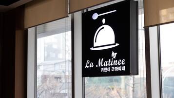 Un letrero con un icono blanco de un plato tapado y el texto 'La Matinee' en inglés y coreano.