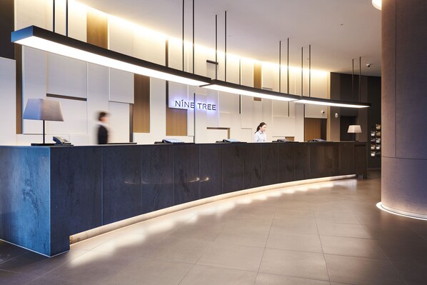 A modern reception area with a curved reception desk, a sign reading "NINE TREE", and a clean, minimalist design. - NINE TREE BY PARNAS SEOUL MYEONDONG 2 (Seoul)