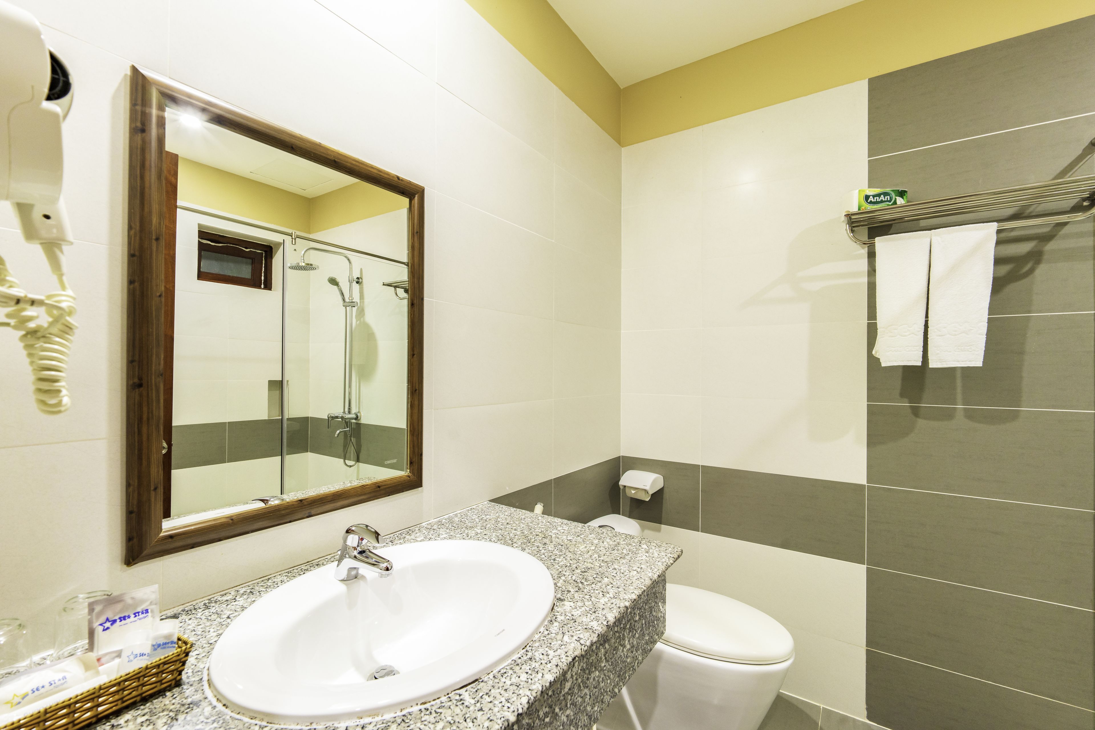 Une salle de bain avec un lavabo blanc, un miroir, une douche et des toilettes.