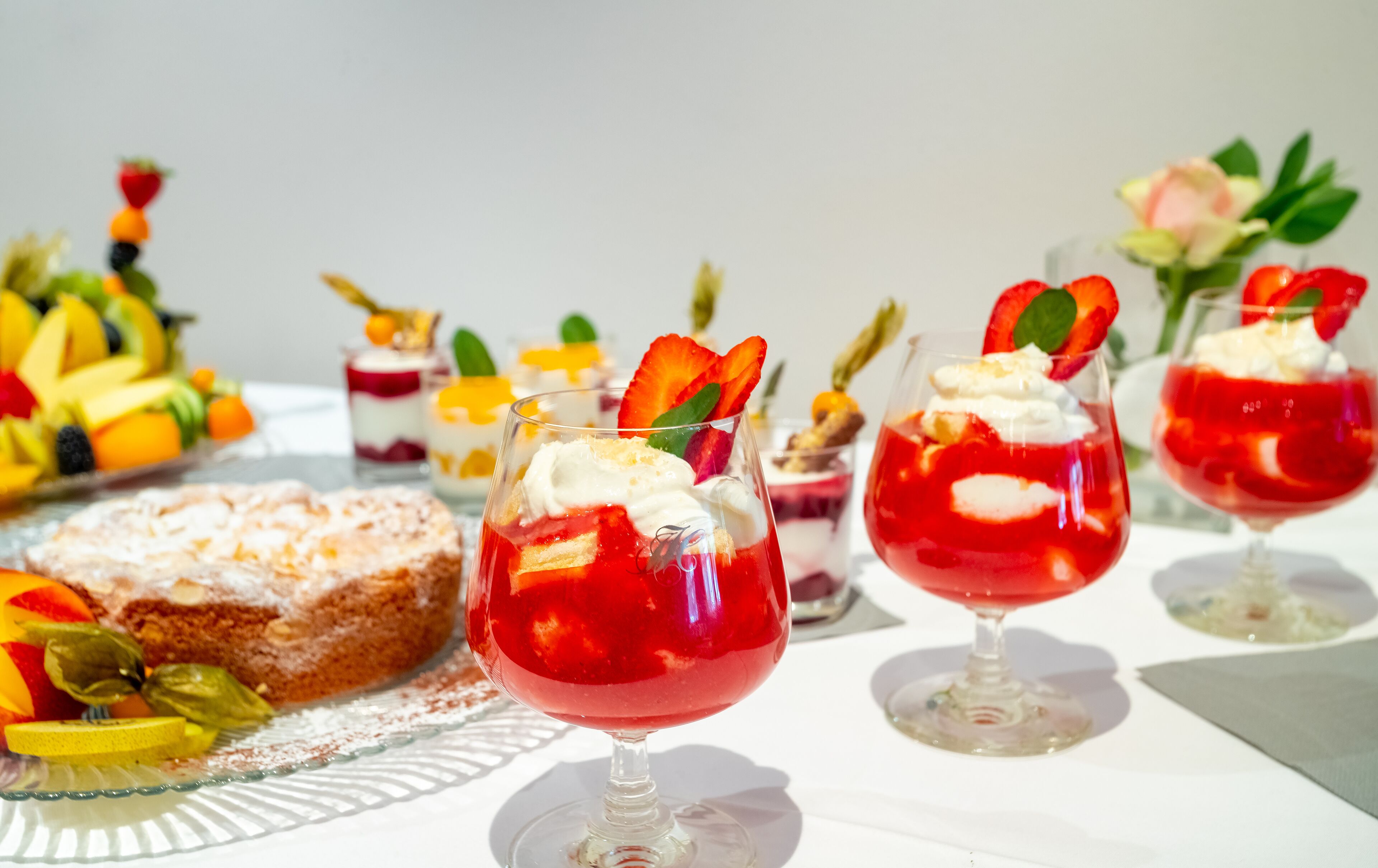 A dessert table with various fruit-based drinks and a cake.