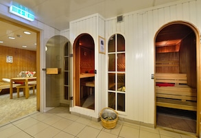 Una sala de sauna con bancos de madera y una pequeña mesa con un vaso de agua.