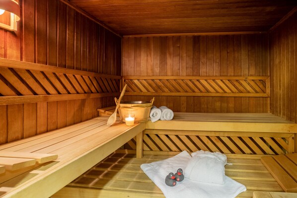 Una sauna con bancos de madera, una vela, toallas y patitos de goma.