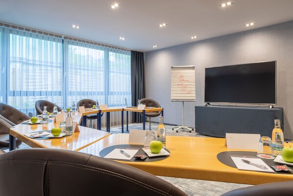 A conference room with a large table, chairs, a projector screen, and a whiteboard.