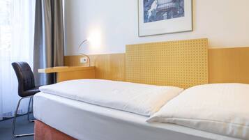Una habitación de hotel con una cama, un escritorio, una silla y un cuadro en la pared.